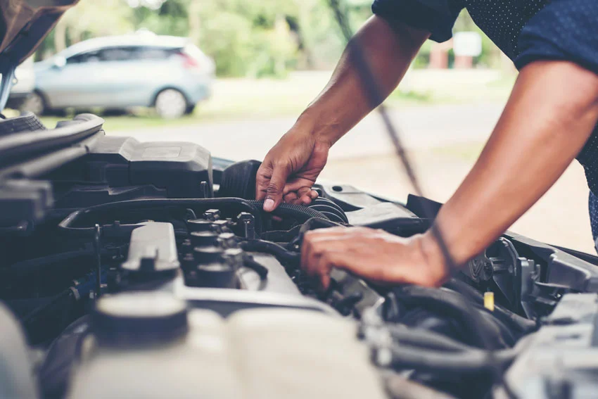 A man working under the hood of a vehicle