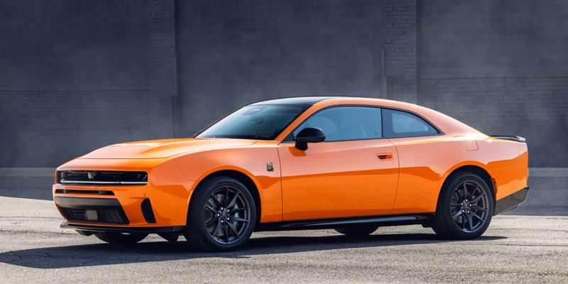 The image features an eye-catching orange Dodge Charger, showcasing its powerful and muscular design with a sleek, sporty aesthetic set against an industrial backdrop.
