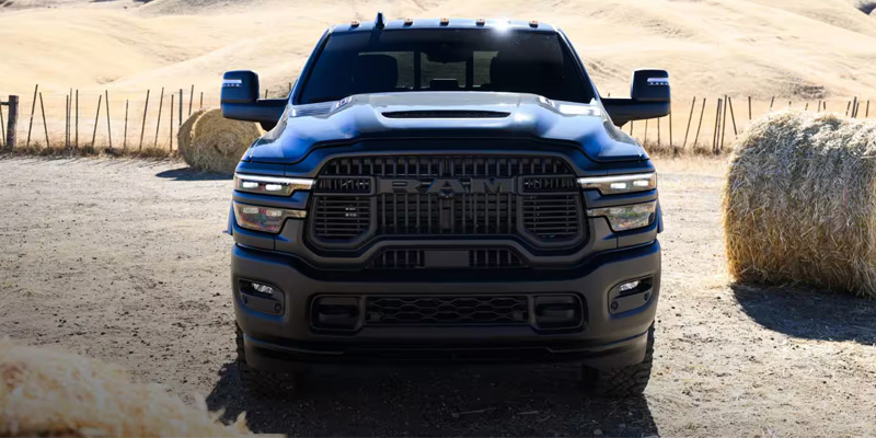 Black RAM heavy-duty pickup on a rural dirt road.