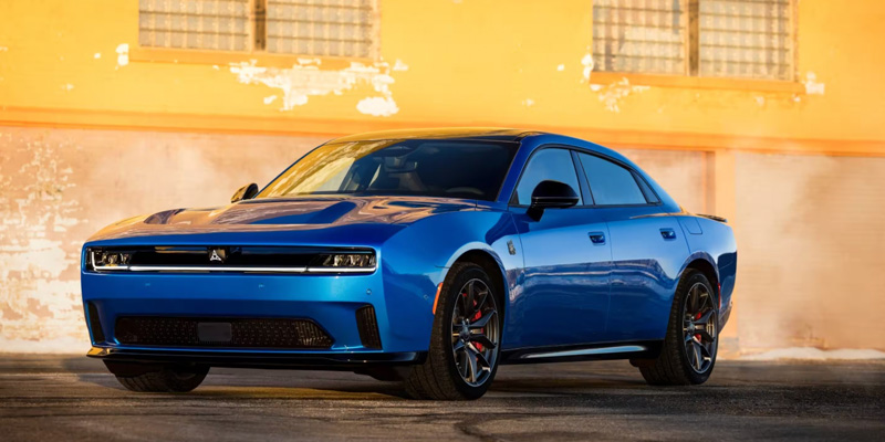 Blue Dodge Charger sedan parked in front of a sunlit building with a bold performance stance.