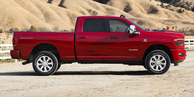 Side profile of a red RAM 2500 pickup truck parked outdoors.